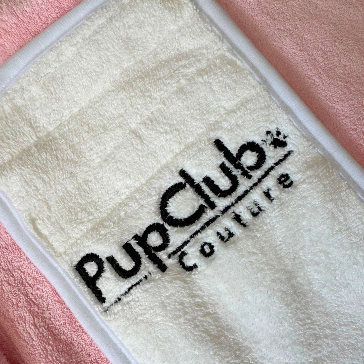Towel with 'Pup Club Couture' logo on a pink background
