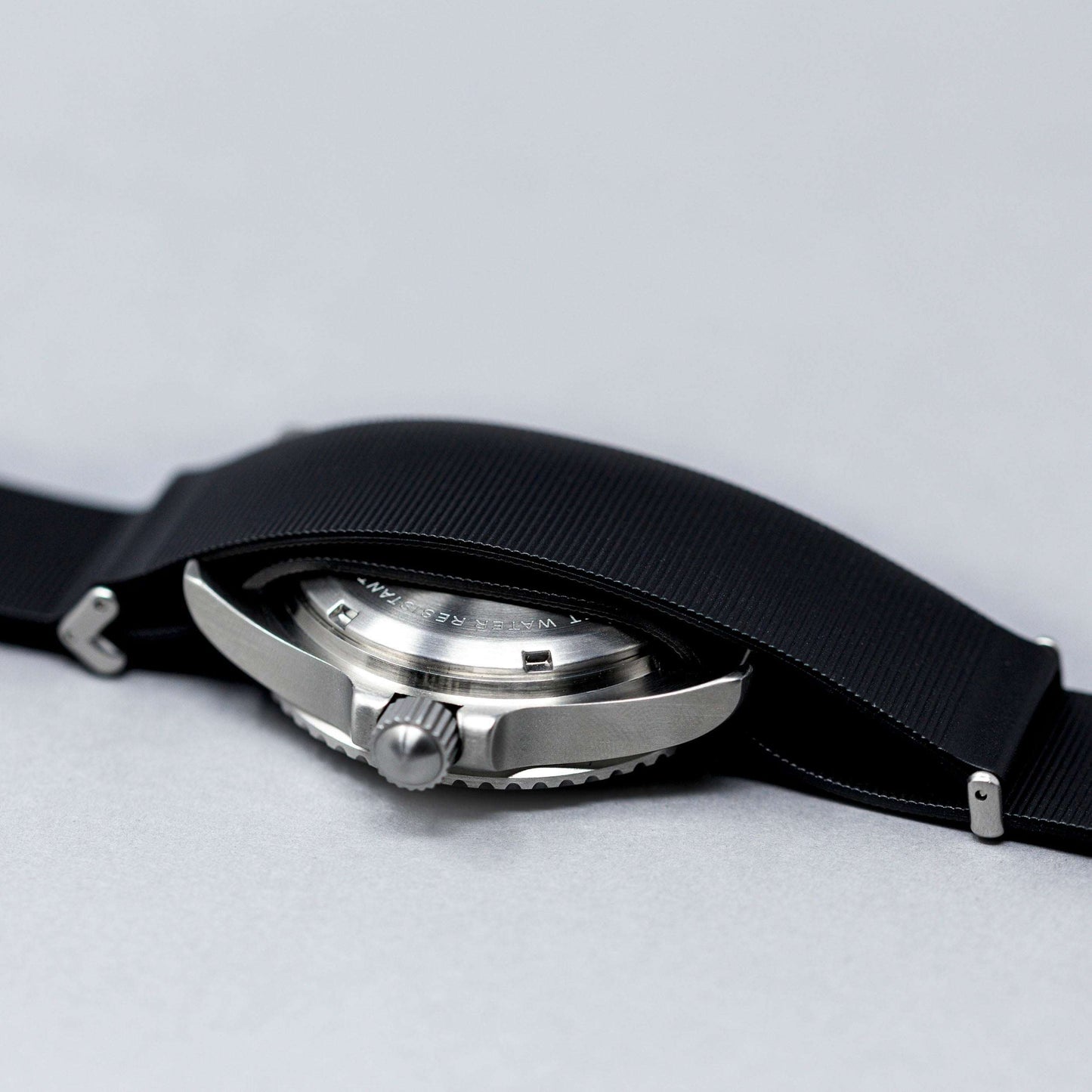 Close-up of a watch with a black strap on a light gray background