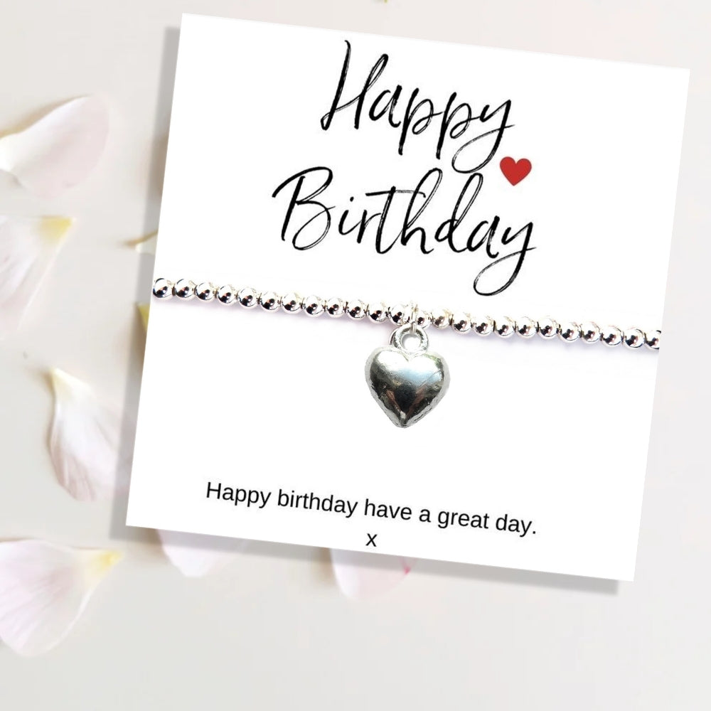 Silver heart charm bracelet on a 'Happy Birthday' card with a white background
