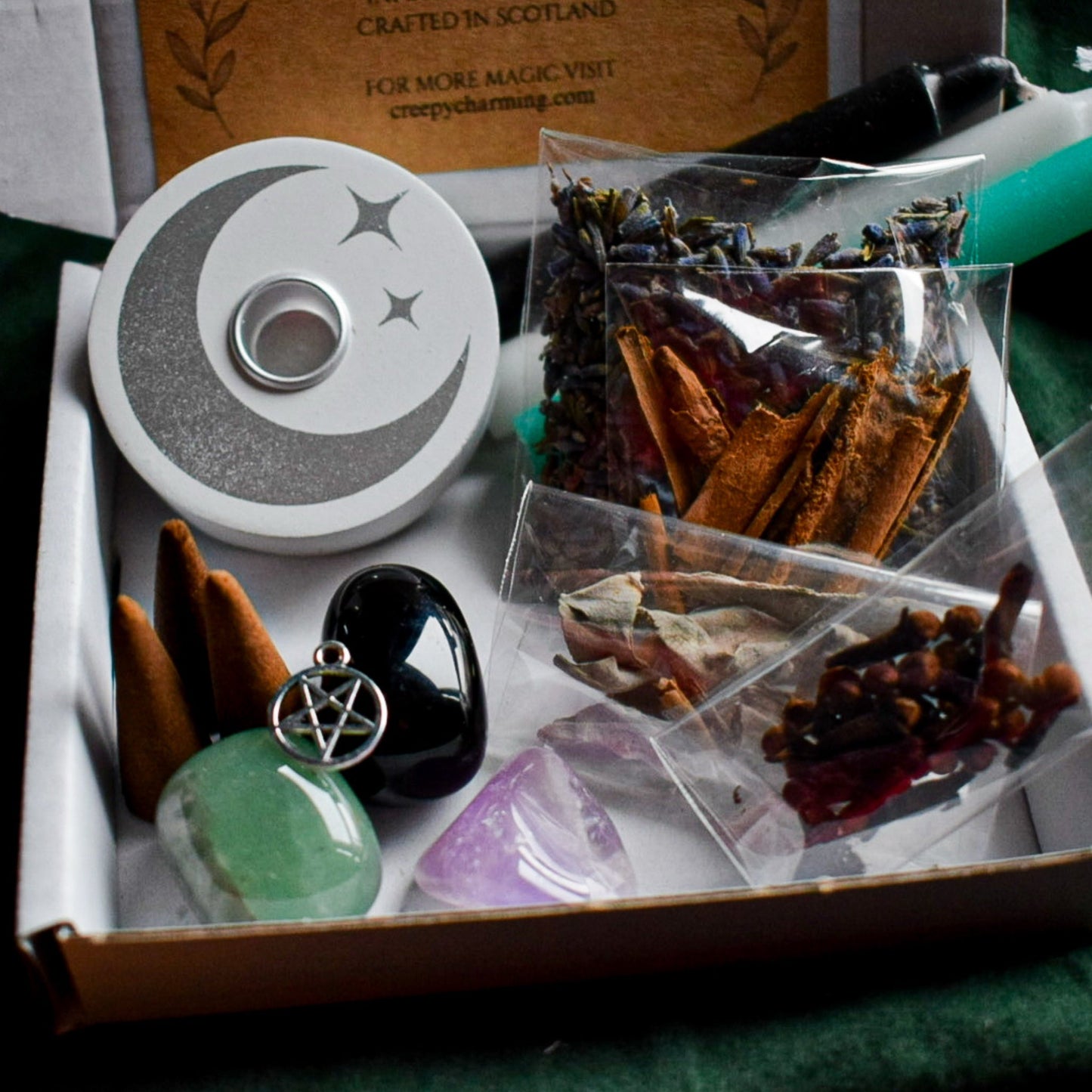 Witchcraft supplies including a pentacle pendant, crystal, and herbs in a box.