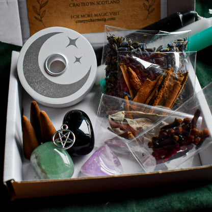 Witchcraft supplies including a pentacle pendant, crystal, and herbs in a box.