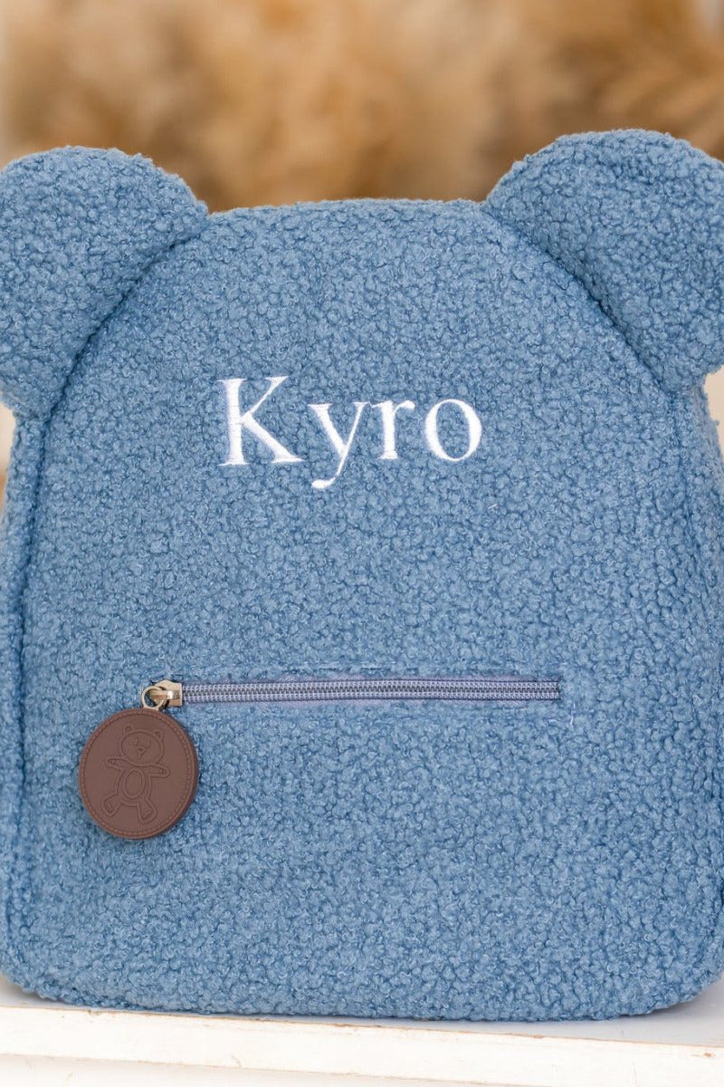 Blue bear-shaped pillow with 'Kyro' branding on a blurred background