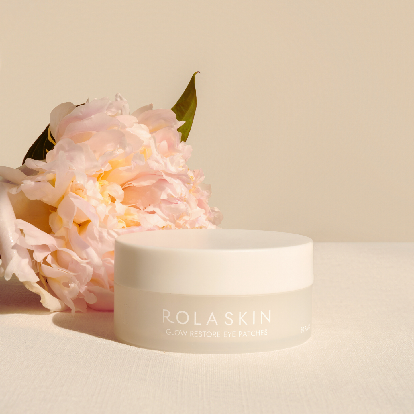 White skincare jar with pink flowers on a beige background