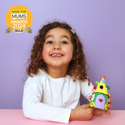 Child holding a colorful toy house with 'Made for Mums Awards 2024 Gold' badge on a purple background
