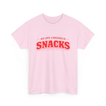A light pink short-sleeve crewneck t-shirt with a red graphic text print reading 'MY LOVE LANGUAGE IS SNACKS' on the chest, displayed against a solid white background.