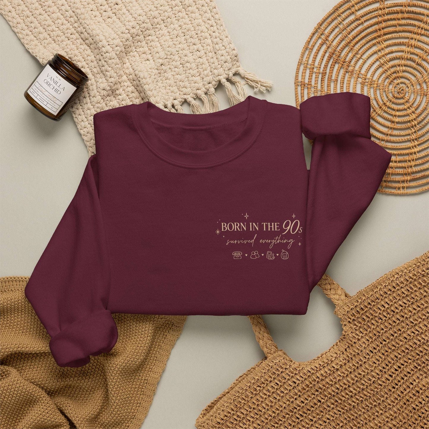Maroon sweatshirt with 'Born in the 90s’ text on a textured surface 