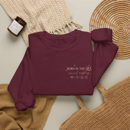 Maroon sweatshirt with 'Born in the 90s’ text on a textured surface 