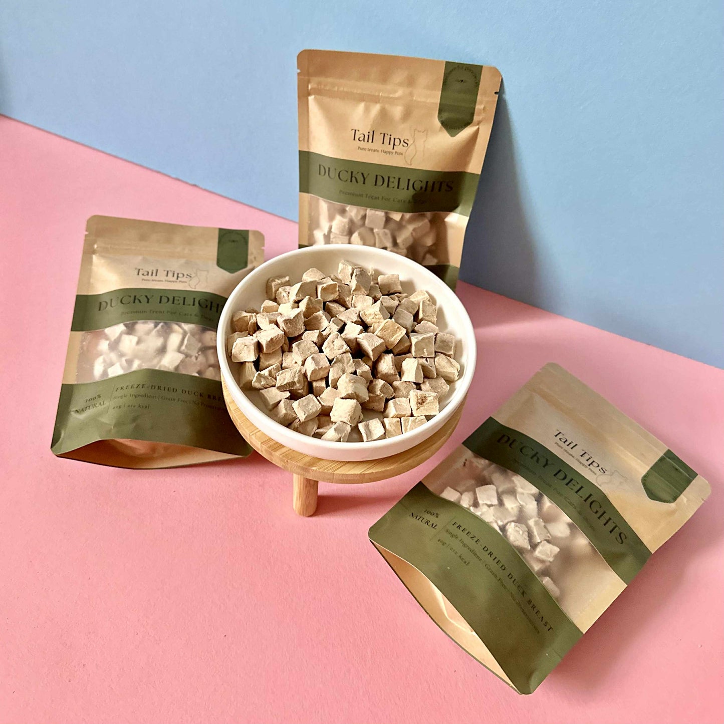 Tail Tips Ducky Delicacies packaging with a bowl of treats on a pink and blue background