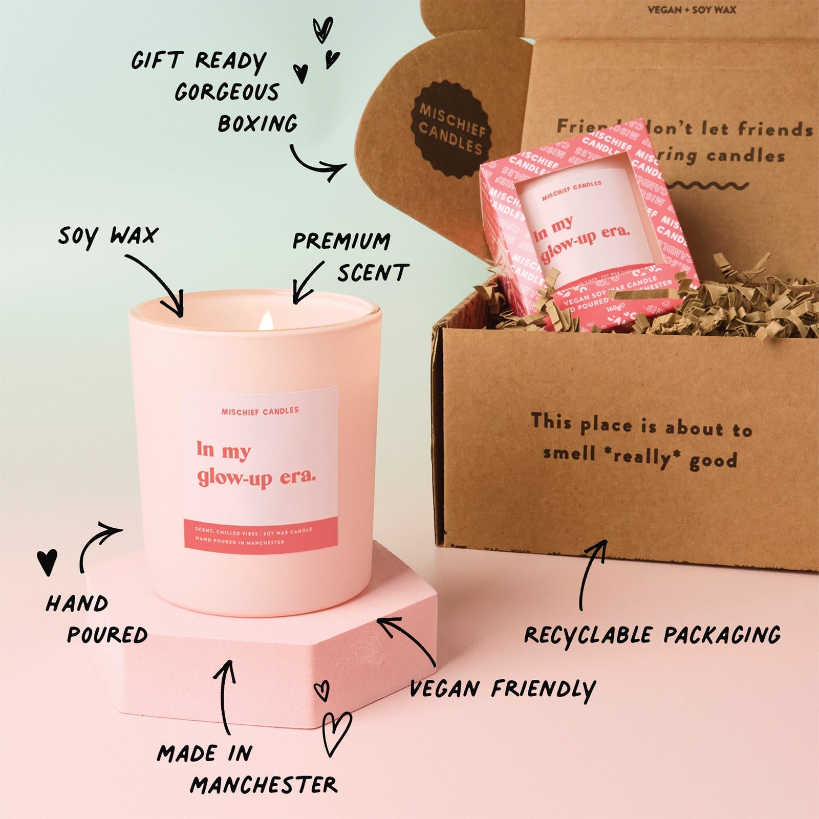 Pink candle with text highlighting features, next to a cardboard box with candles inside.