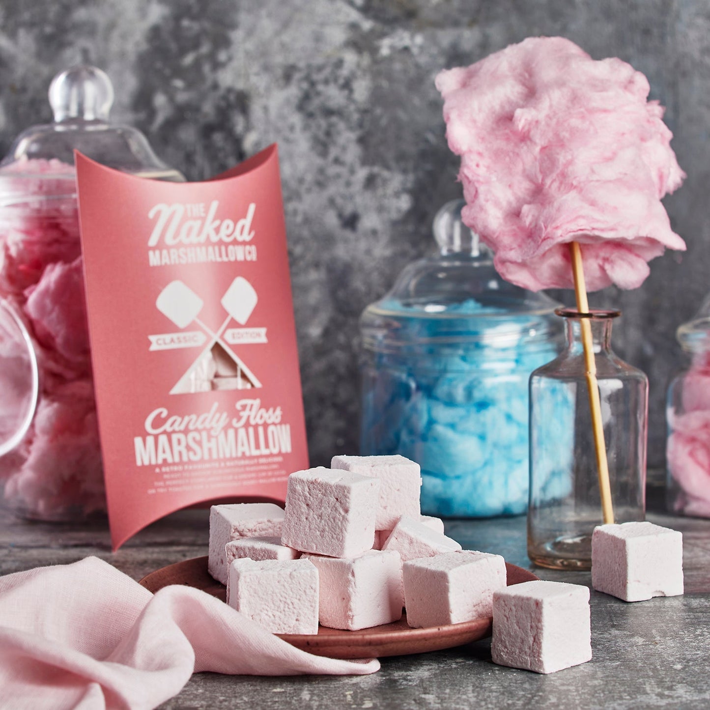 Naked Marshmallows candy floss marshmallows with packaging and cotton candy in the background.