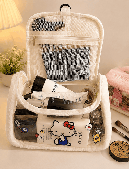 White travel toiletry bag with cosmetic products including a Chanel bottle, on a light surface.