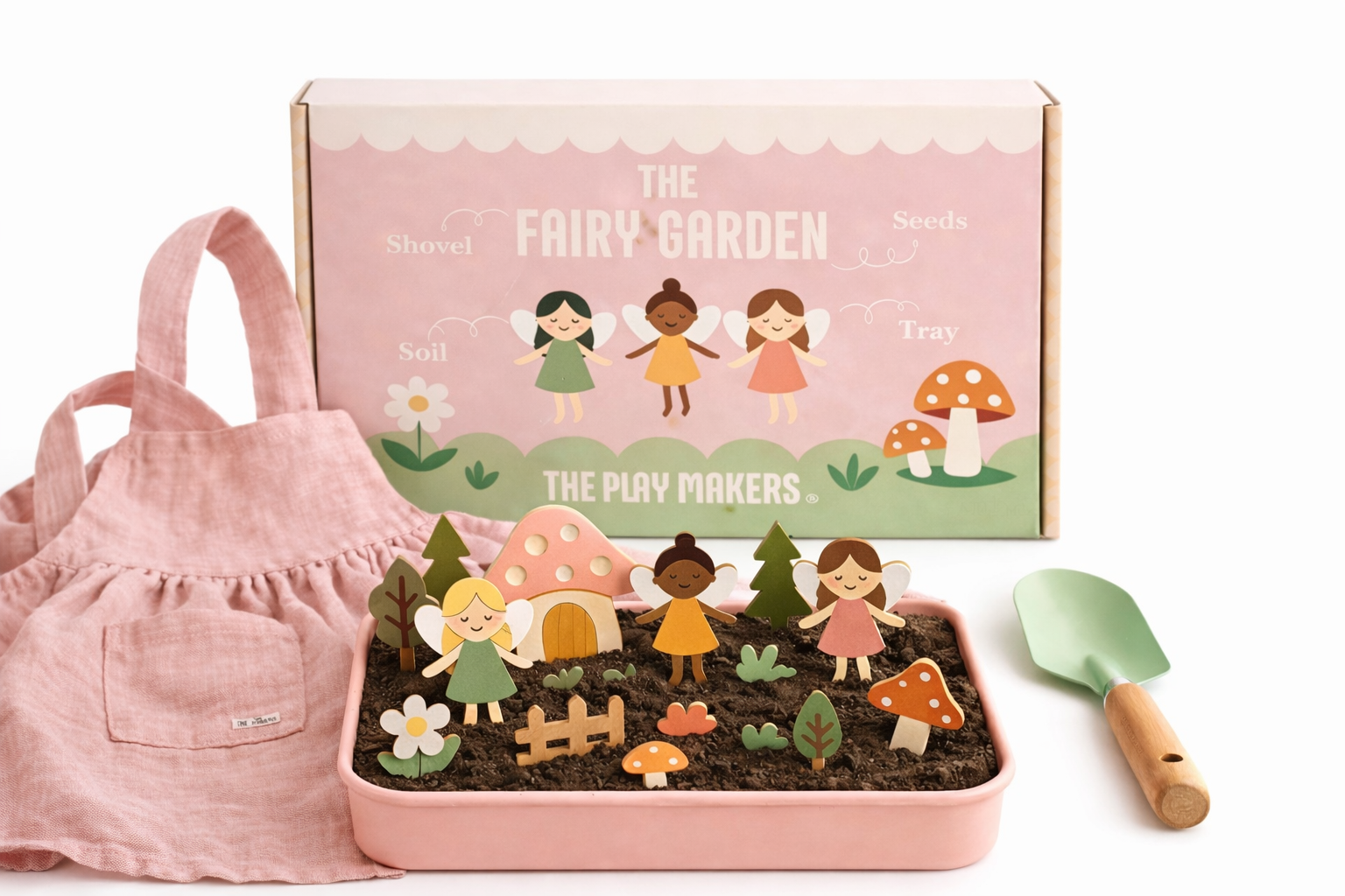 Fairy garden set with fairy figures, mushroom, and flower in a pink tray with a pink apron and trowel on a white background.