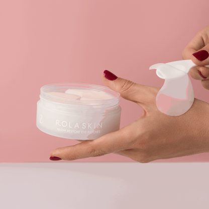 Rolaskin eye patches with a hand holding a container and applying them against a pink background