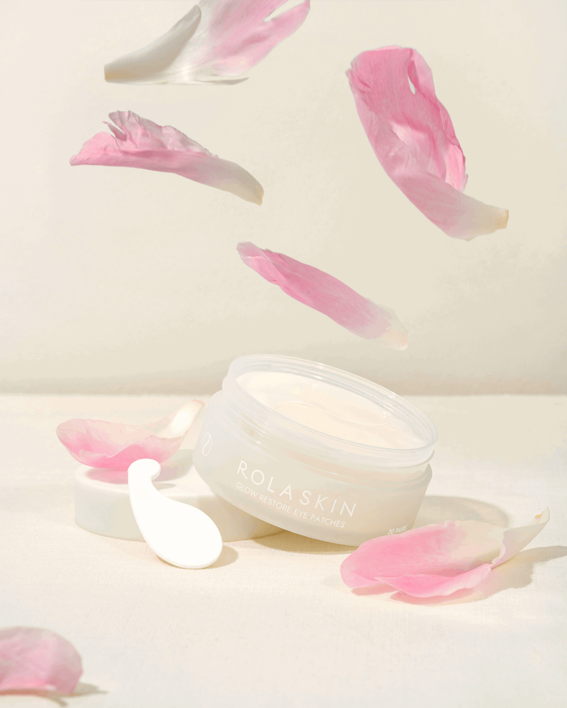 Skincare product with pink petals on a light background