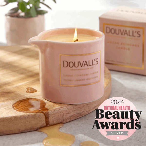 Pink Douvall's candle on a wooden board with a 2024 Natural Health Beauty Awards badge.