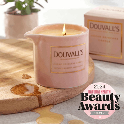 Pink Douvall's candle on a wooden board with a 2024 Natural Health Beauty Awards badge.