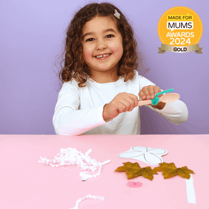 Child playing with craft materials on a pink table against a purple background, with a 'Made for Mums Awards 2024 Gold' badge.
