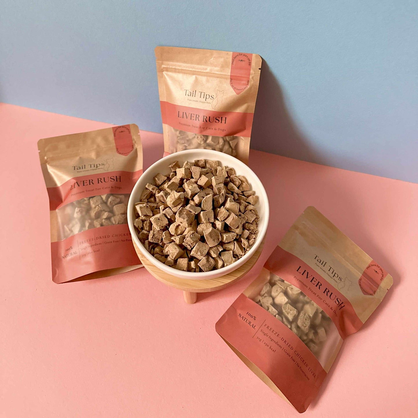 Dog treats in packaging with a bowl of treats on a pink and blue background
