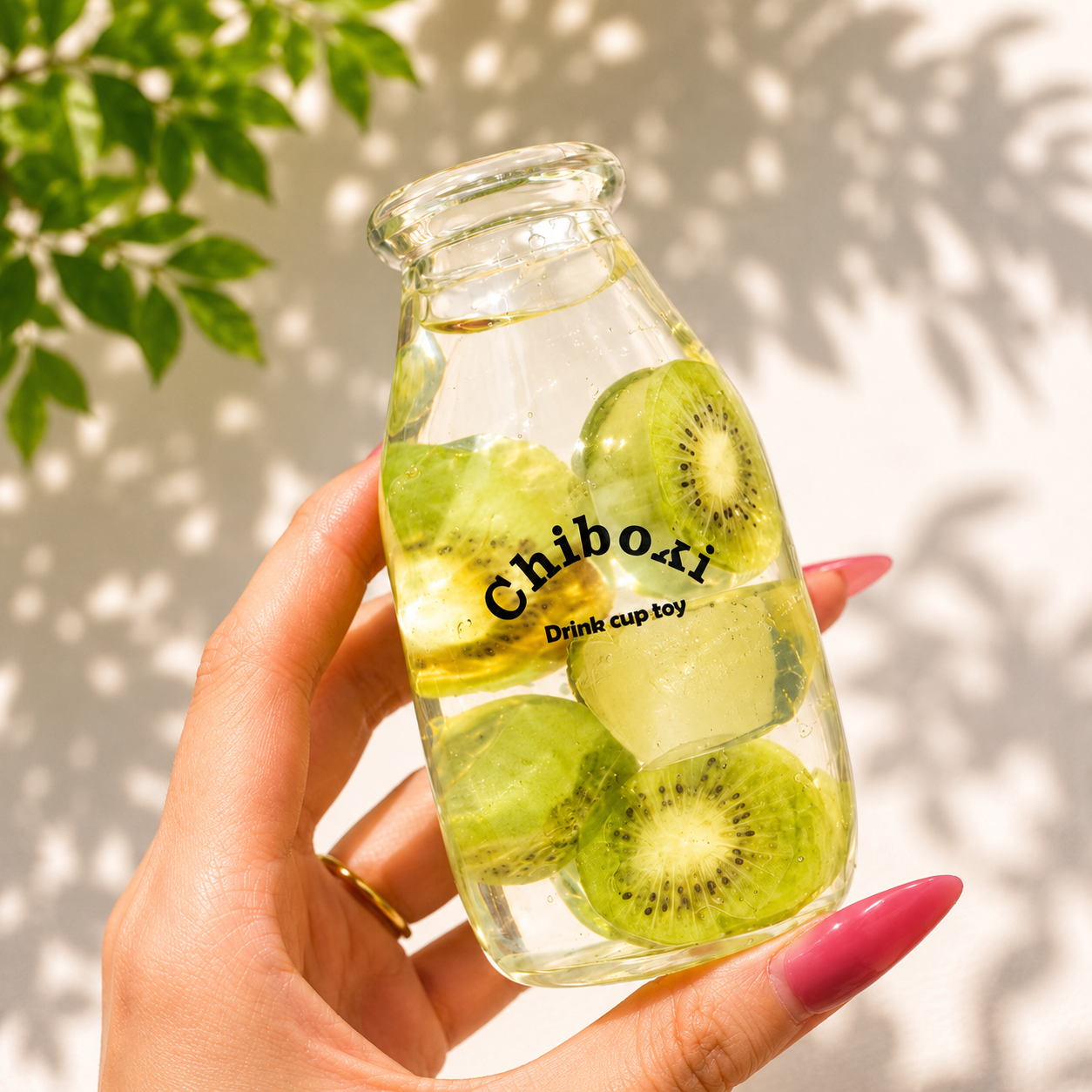 Glass bottle with sliced kiwis labeled 'Chiboki' held by a hand against a light background.