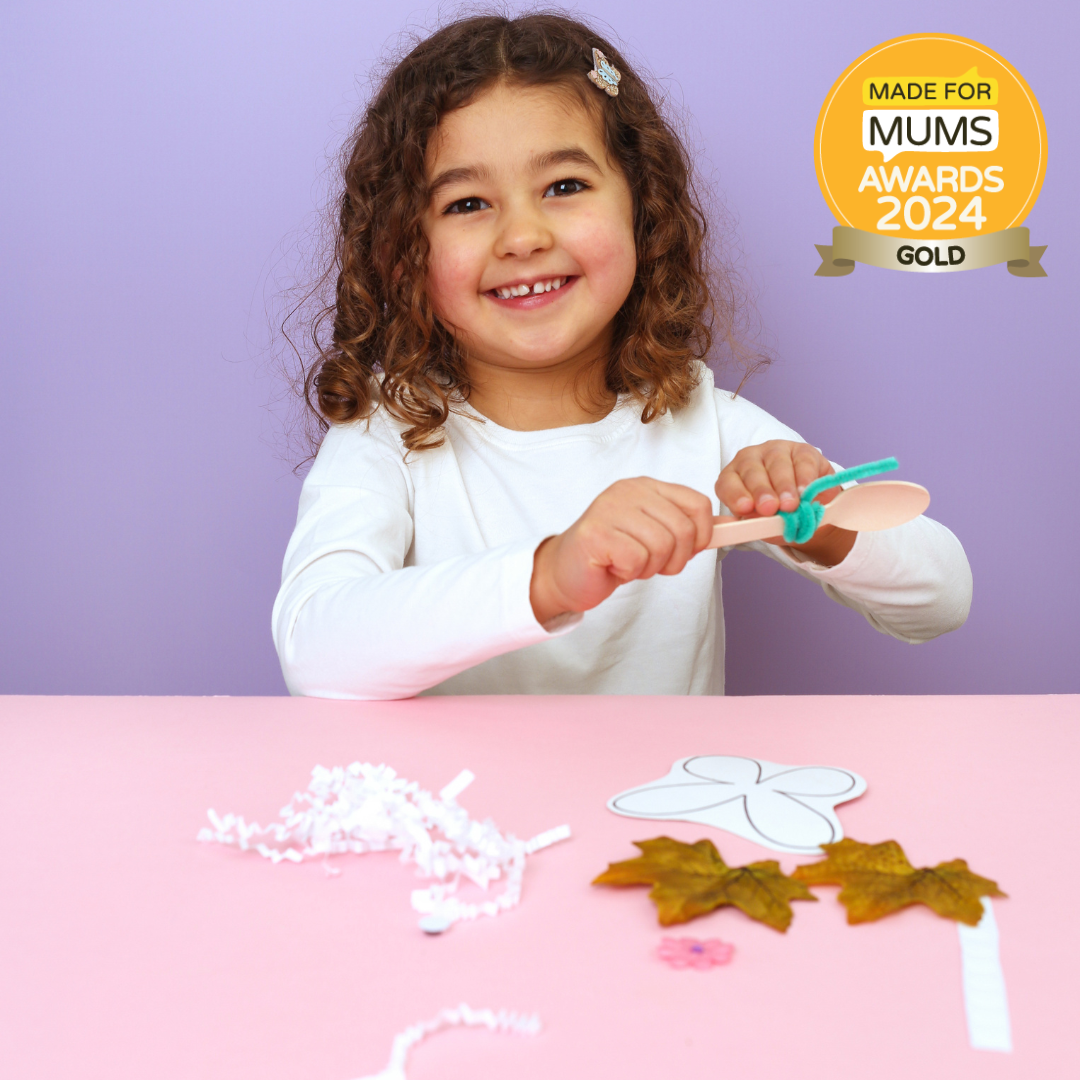 Child playing with craft materials on a pink table against a purple background, with a 'Made for Mums Awards 2024 Gold' badge.