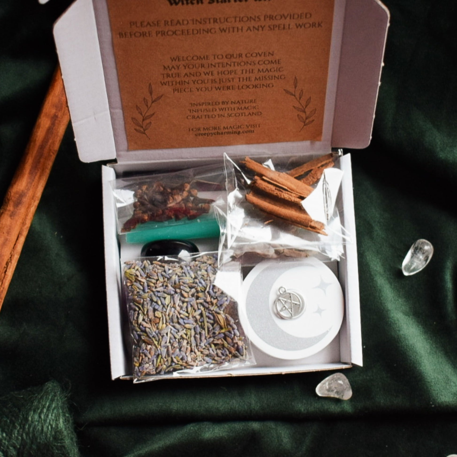 Witch Starter Kit with lavender, cinnamon sticks, and other items on a green fabric background