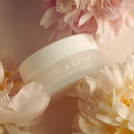 Rolaskin eye patch container surrounded by flowers on a soft pink background