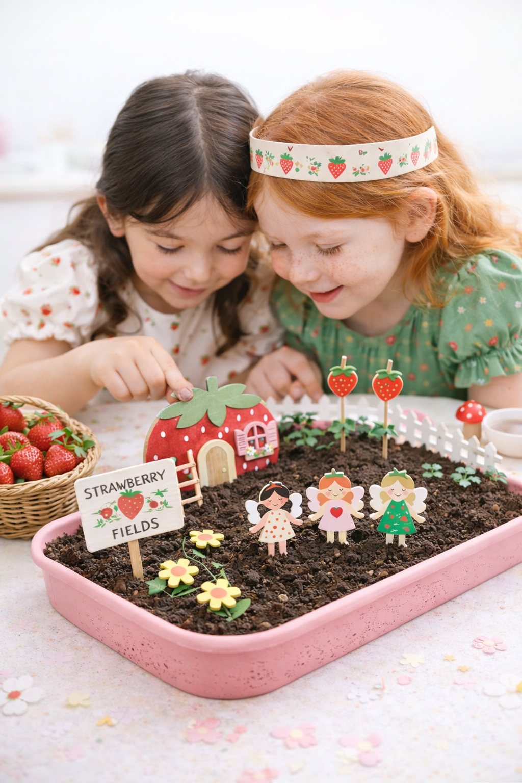 Two children playing with a miniature garden set on a table.