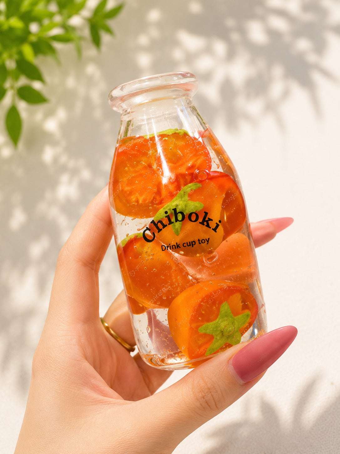 Glass bottle with orange slices and 'Chiboki' branding held by a hand against a light background.