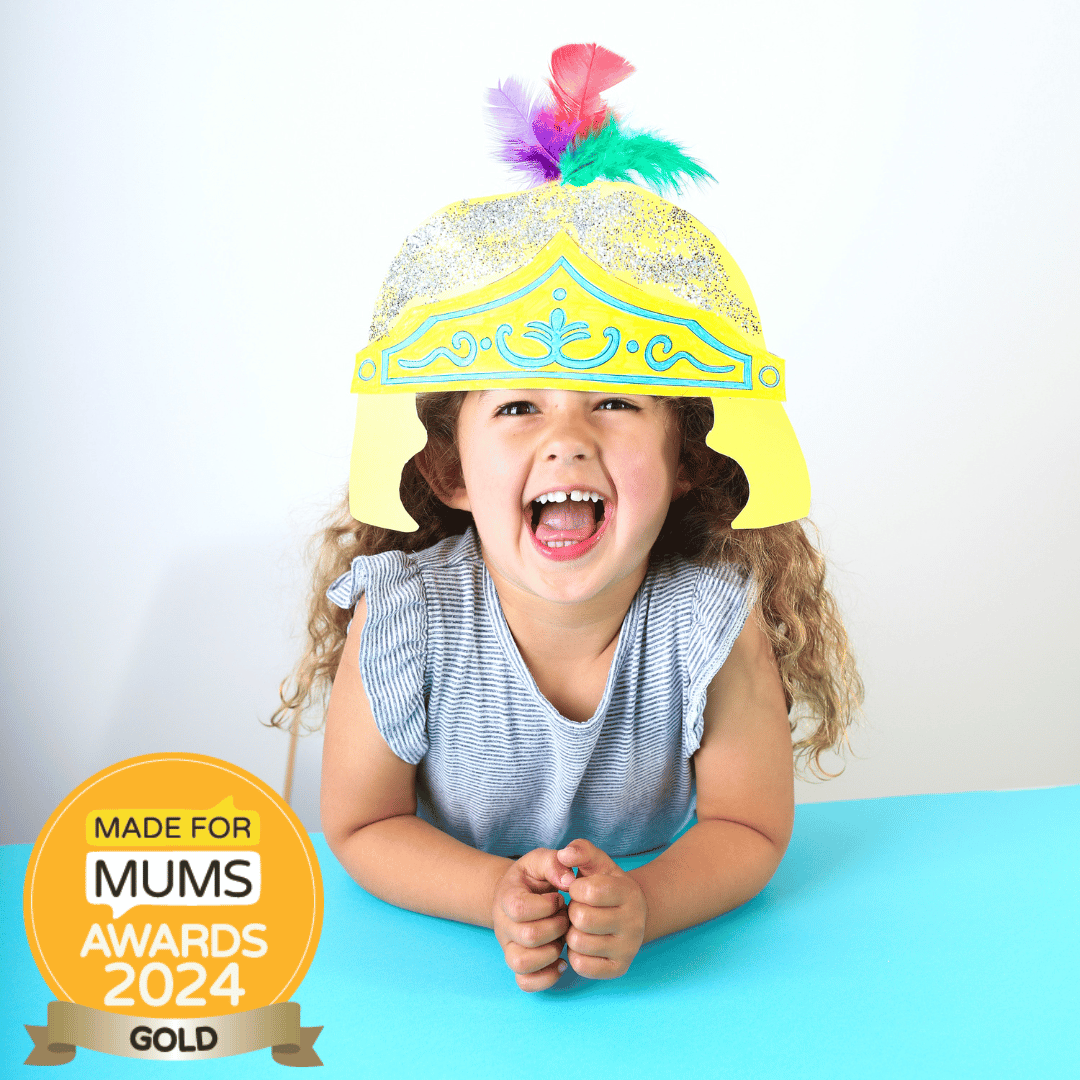 Child wearing a colorful hat with feathers, sitting on a blue surface, and a 'Made for Mums Awards 2024 Gold' badge.