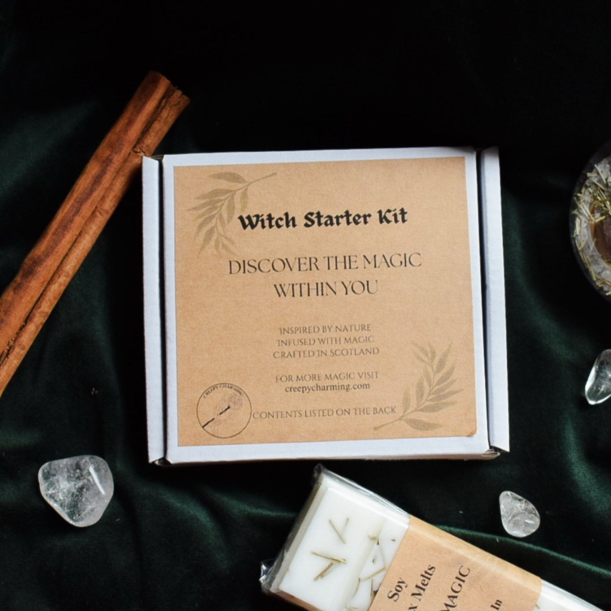 Witch Starter Kit packaging with crystals and a candle on a dark fabric background