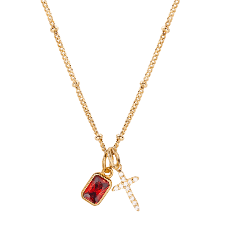 Gold necklace with a red gemstone pendant and cross charm on a white background