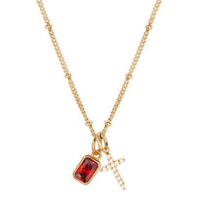 Gold necklace with a red gemstone pendant and cross charm on a white background