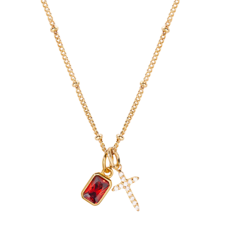 Gold necklace with a red gemstone pendant and cross charm on a white background