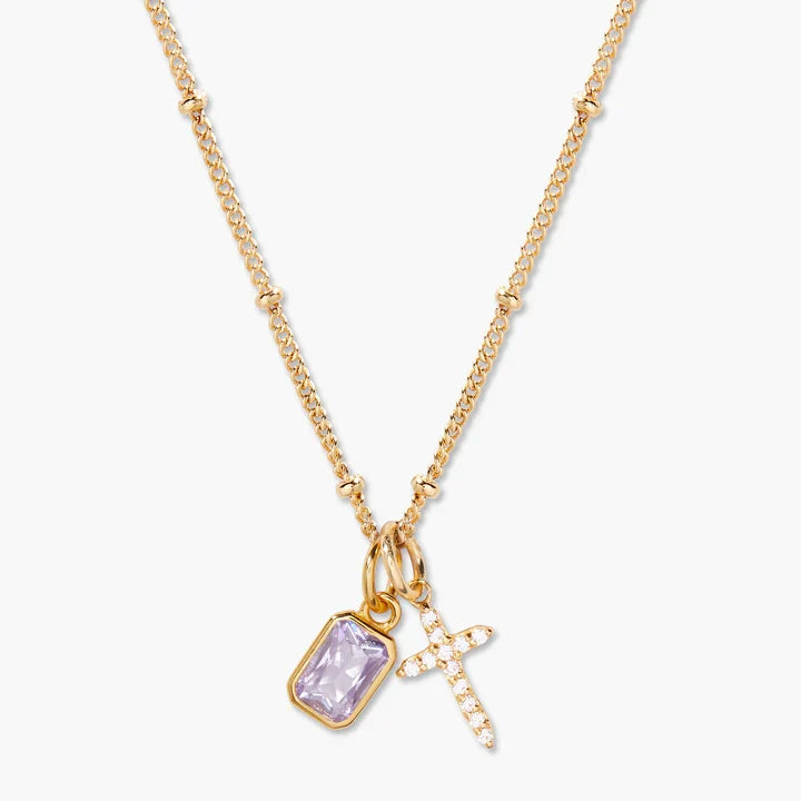 Gold necklace with a purple pendant and cross charm on a white background