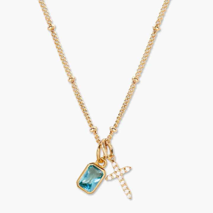 Gold necklace with blue gemstone and cross pendant on a white background