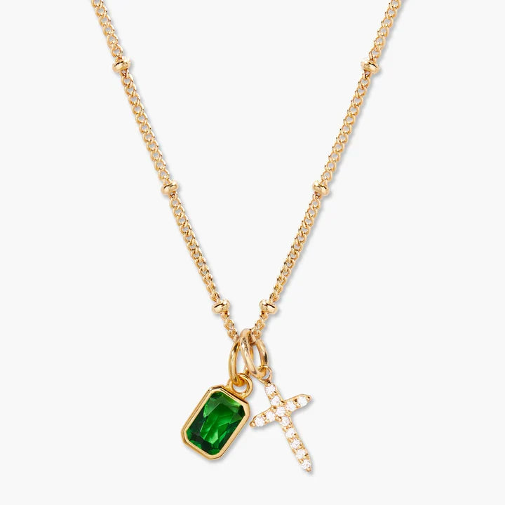 Gold necklace with a blue pendant and cross charm on a white background