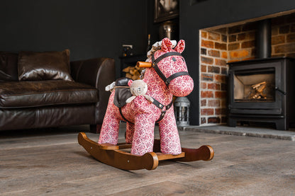 Pink rocking horse toy in a living room with a fireplace.
