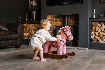Child playing with a rocking horse in a cozy living room.