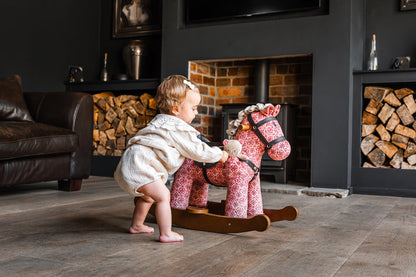 Child playing with a rocking horse in a cozy living room.