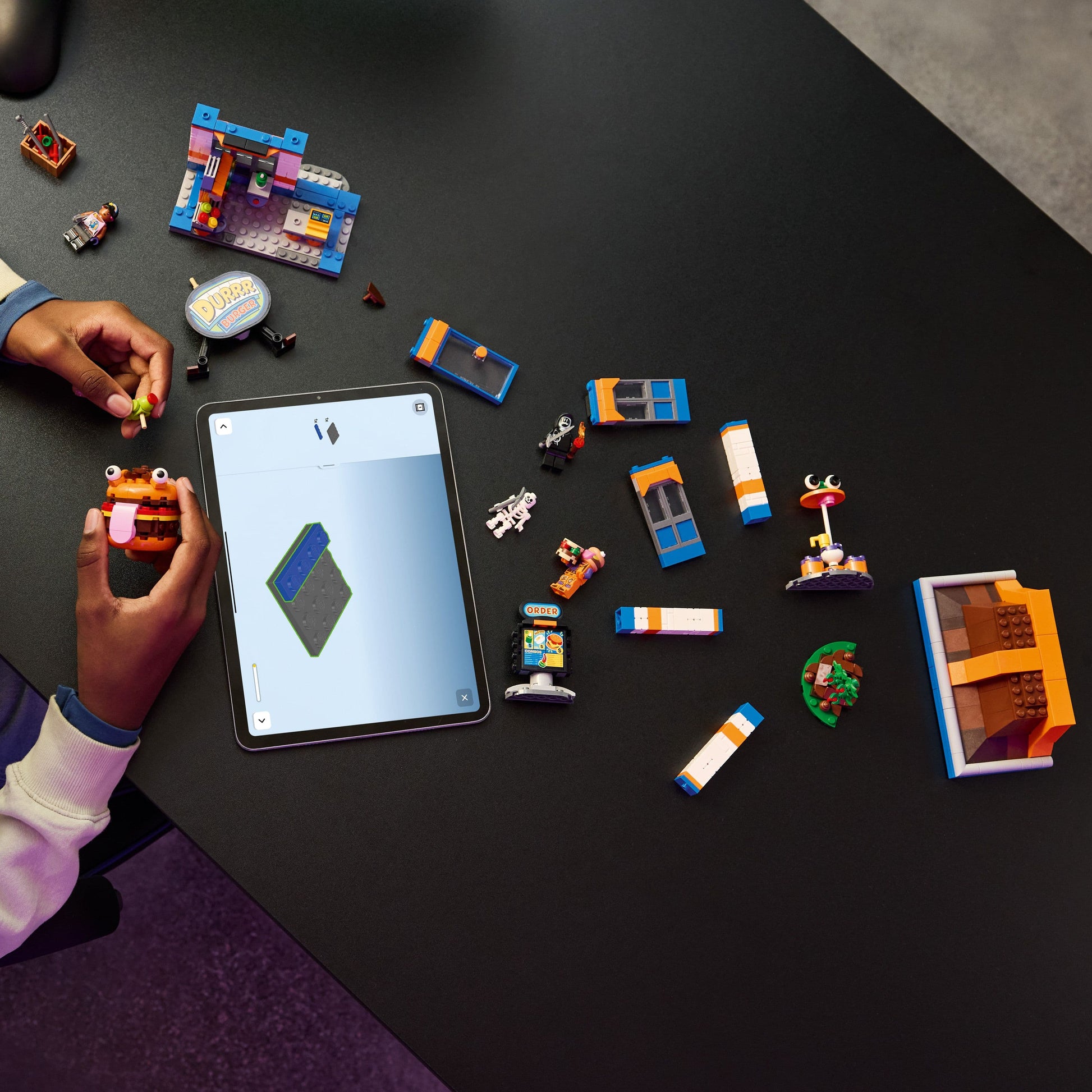 Person using a tablet with augmented reality app on a table with LEGO pieces.