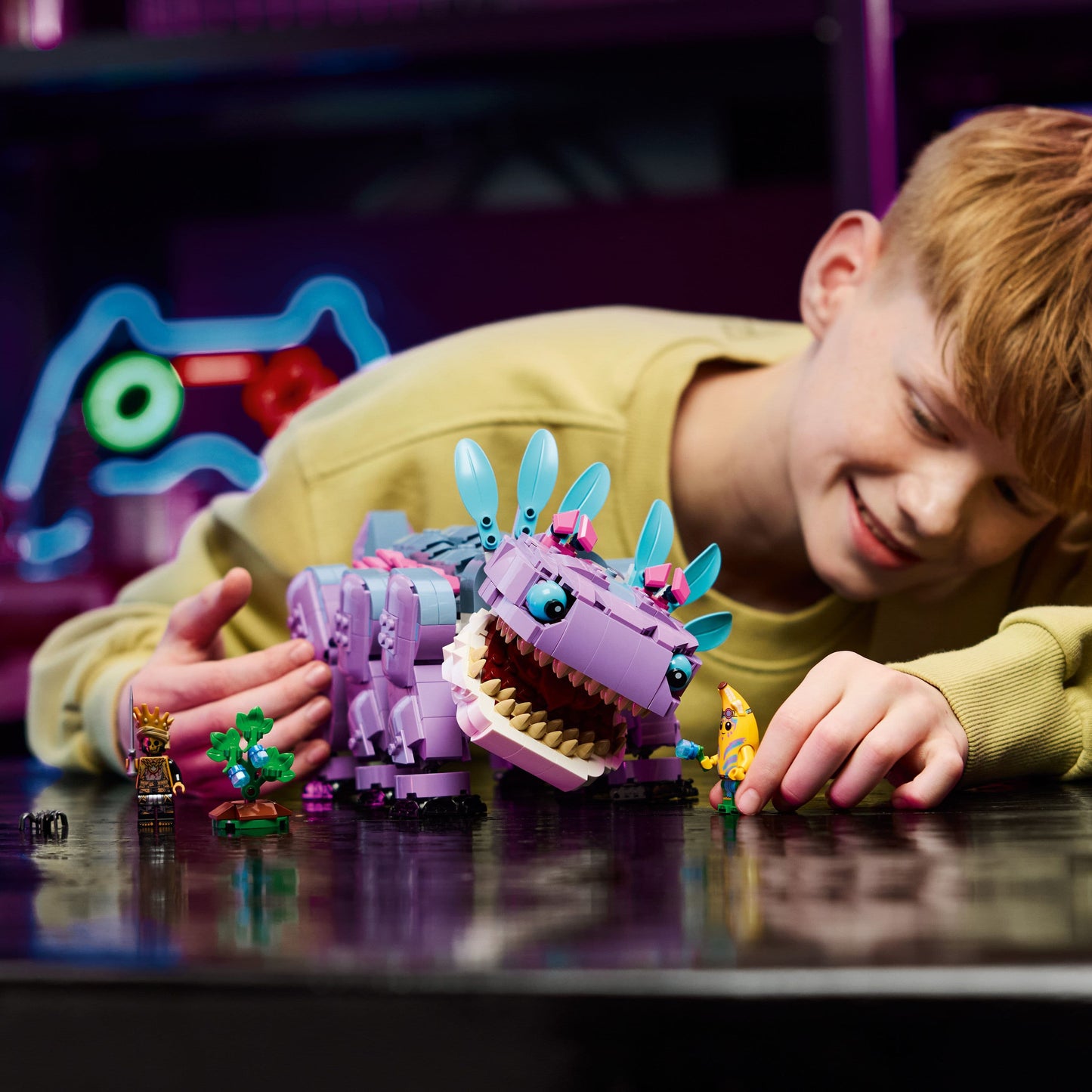 Child playing with a purple and blue toy creature on a dark surface.