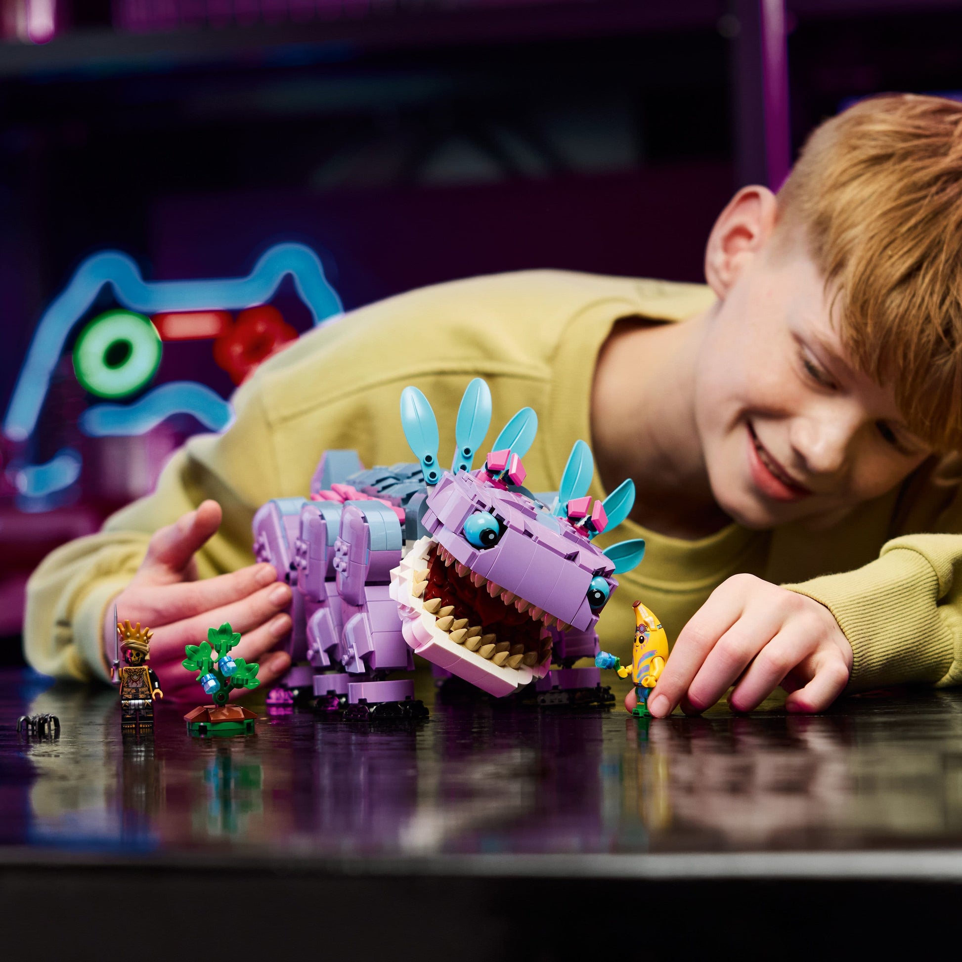 Child playing with a purple and blue toy creature on a dark surface.