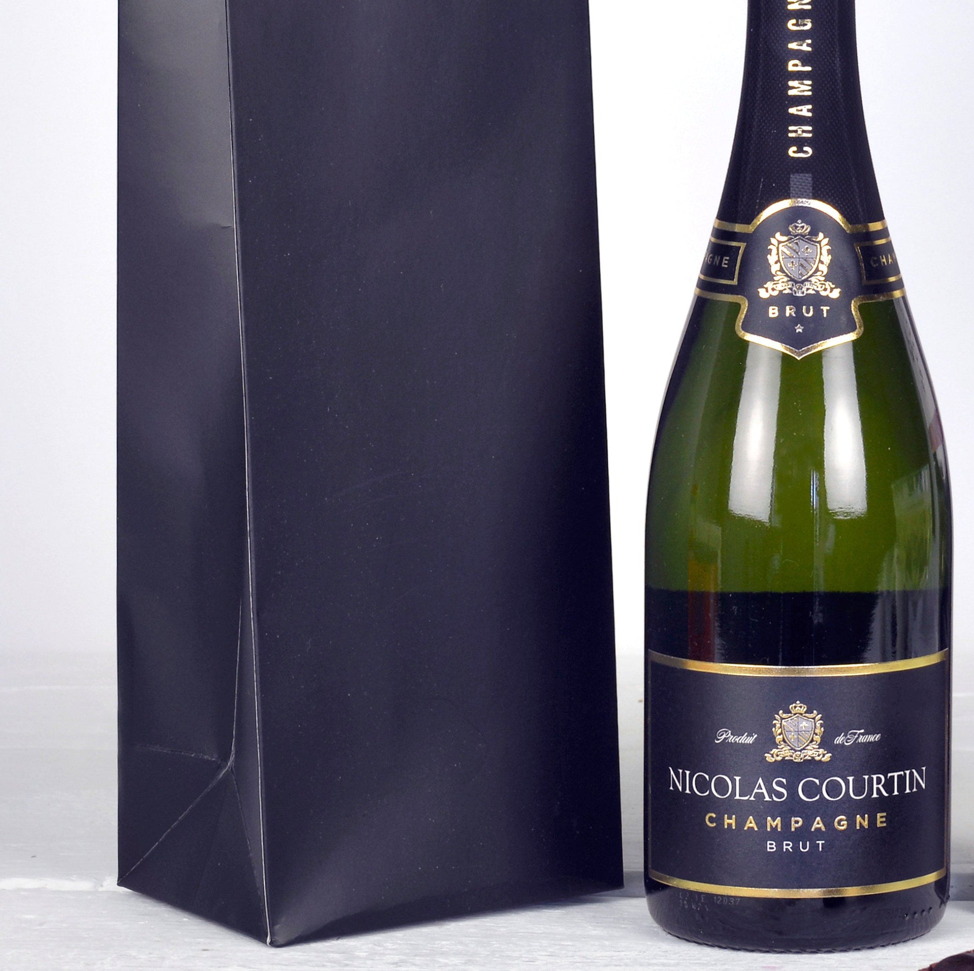 Bottle of Nicolas Courtin Champagne with a matching black gift bag on a white background