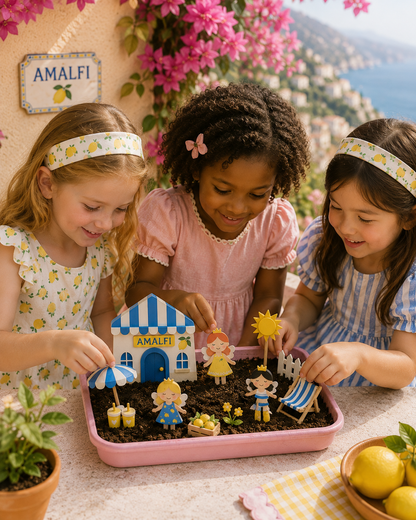 Three children playing with a miniature garden set on a table with a scenic background.