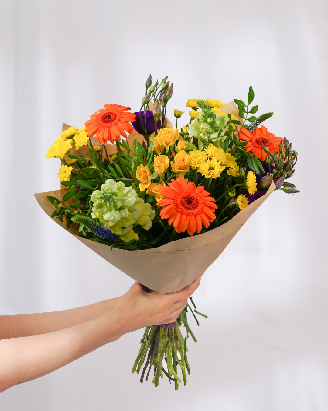 Bouquet of colorful flowers held by a person against a light gray background
