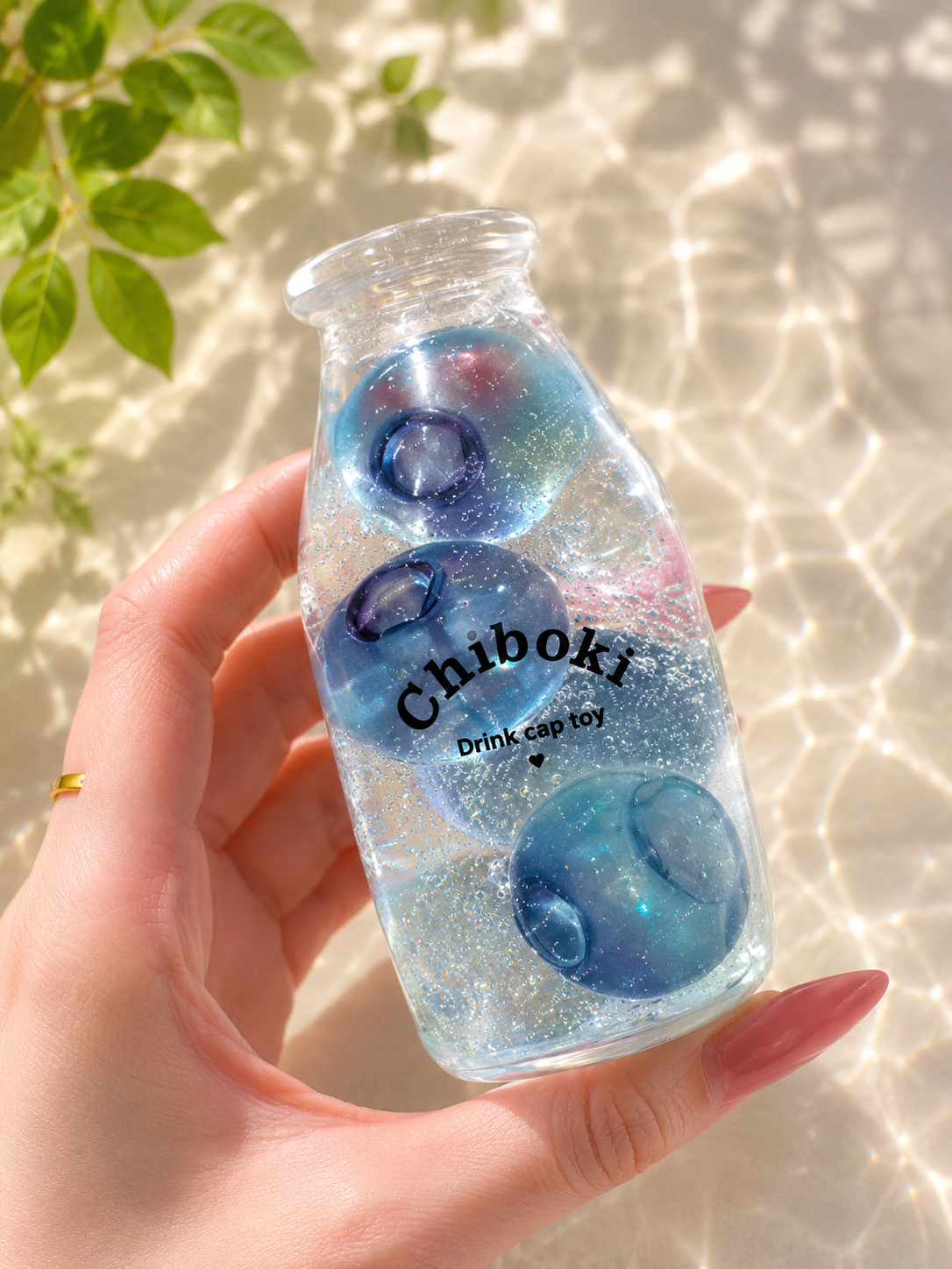 Hand holding a bottle with blue and pink gelatinous balls labeled 'Chiboki' against a light background.