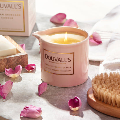 Douvall's candle with pink petals and a brush on a light surface
