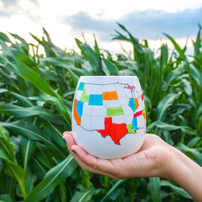 Hand holding a colorful map of the United States against a green field background