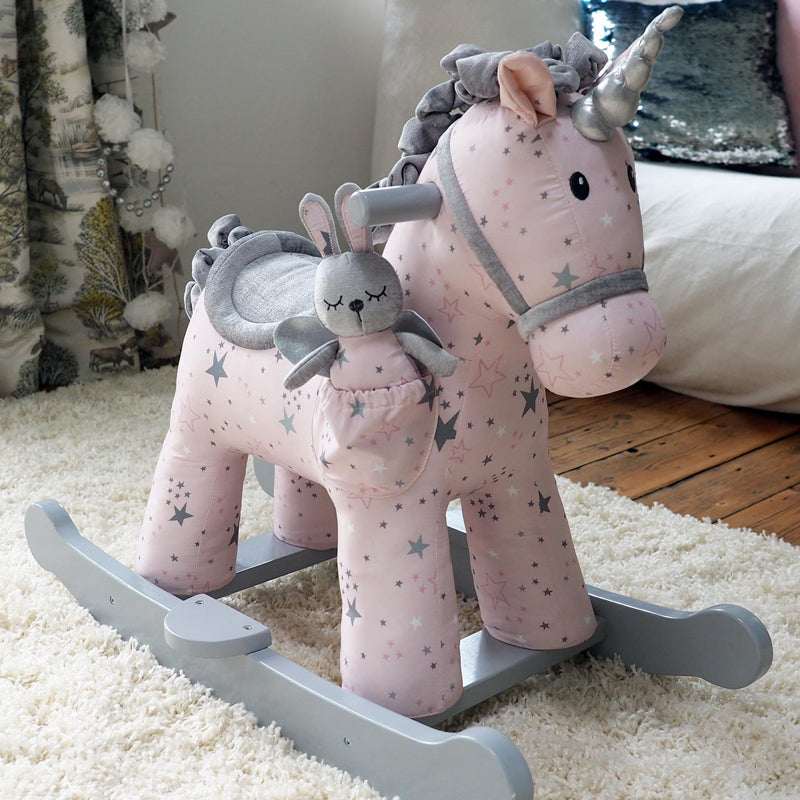 Pink rocking horse with a gray bunny toy on a carpeted floor.