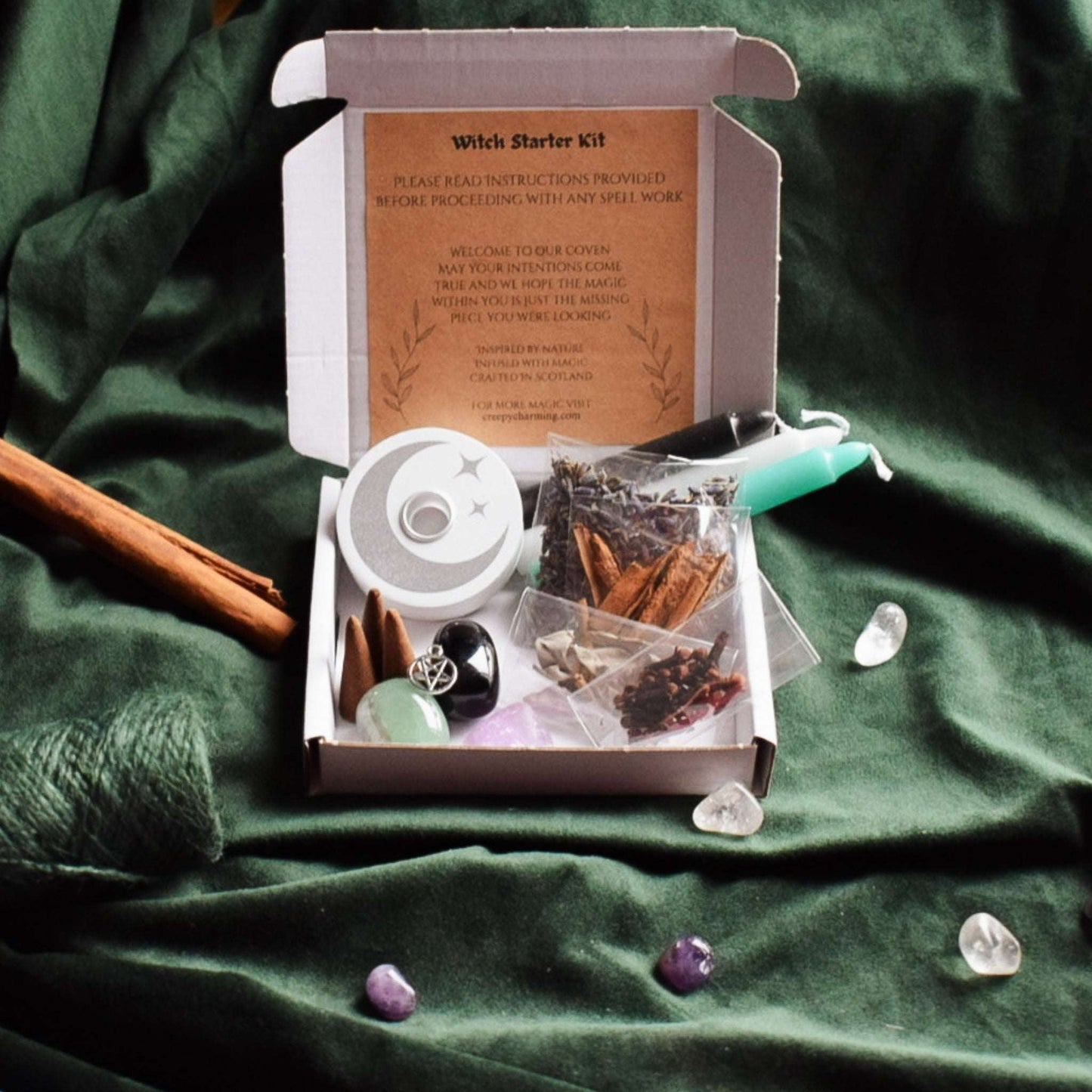 Witch starter kit with spellbook and crystals on a green fabric background
